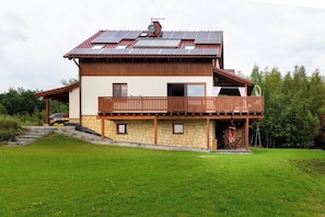 A two-story house with a balcony, solar panels, and a stone foundation. - House with a View, Mucharz 405 (Mucharz)