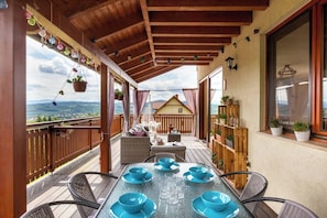 Un patio al aire libre cubierto con mesa lista para comer, una zona de estar y vistas del paisaje.