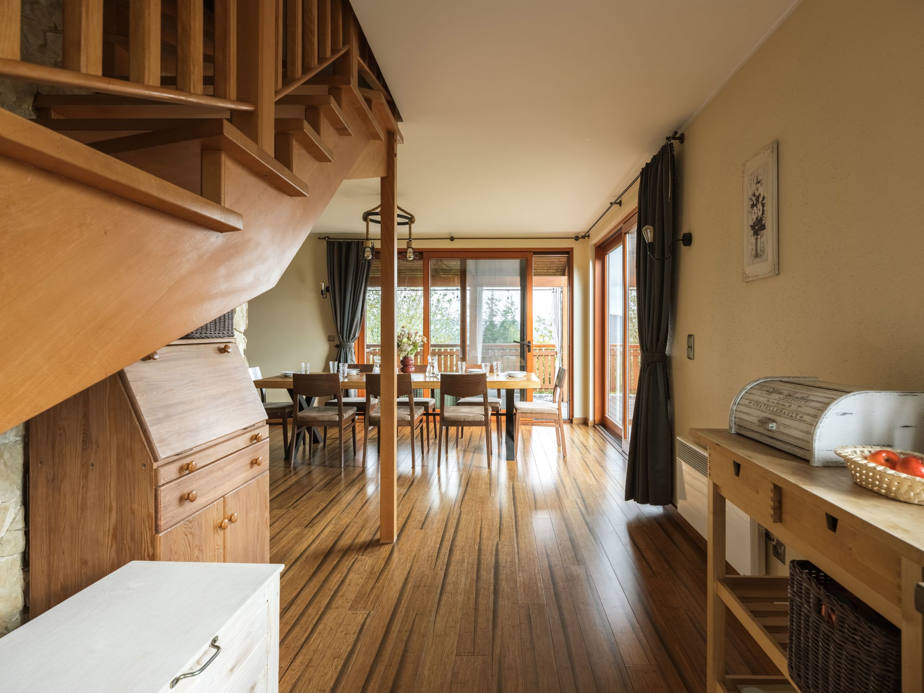 A wooden staircase leading to a dining area with a view of the outdoors.