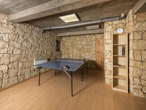 A ping pong table in a room with stone walls and a wooden floor.
