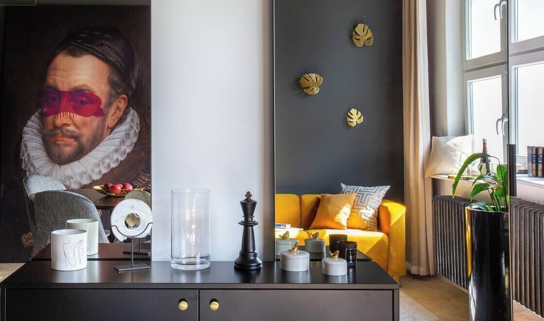 Ein modernes Wohnzimmer mit einem dunkelgrauen Sofa, einem Glastisch und einem großen Gemälde an der Wand.