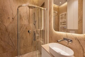 A modern bathroom with a glass-enclosed shower, a white sink, and a marble wall. - Canvas House Apartament Oasis (Kraków)