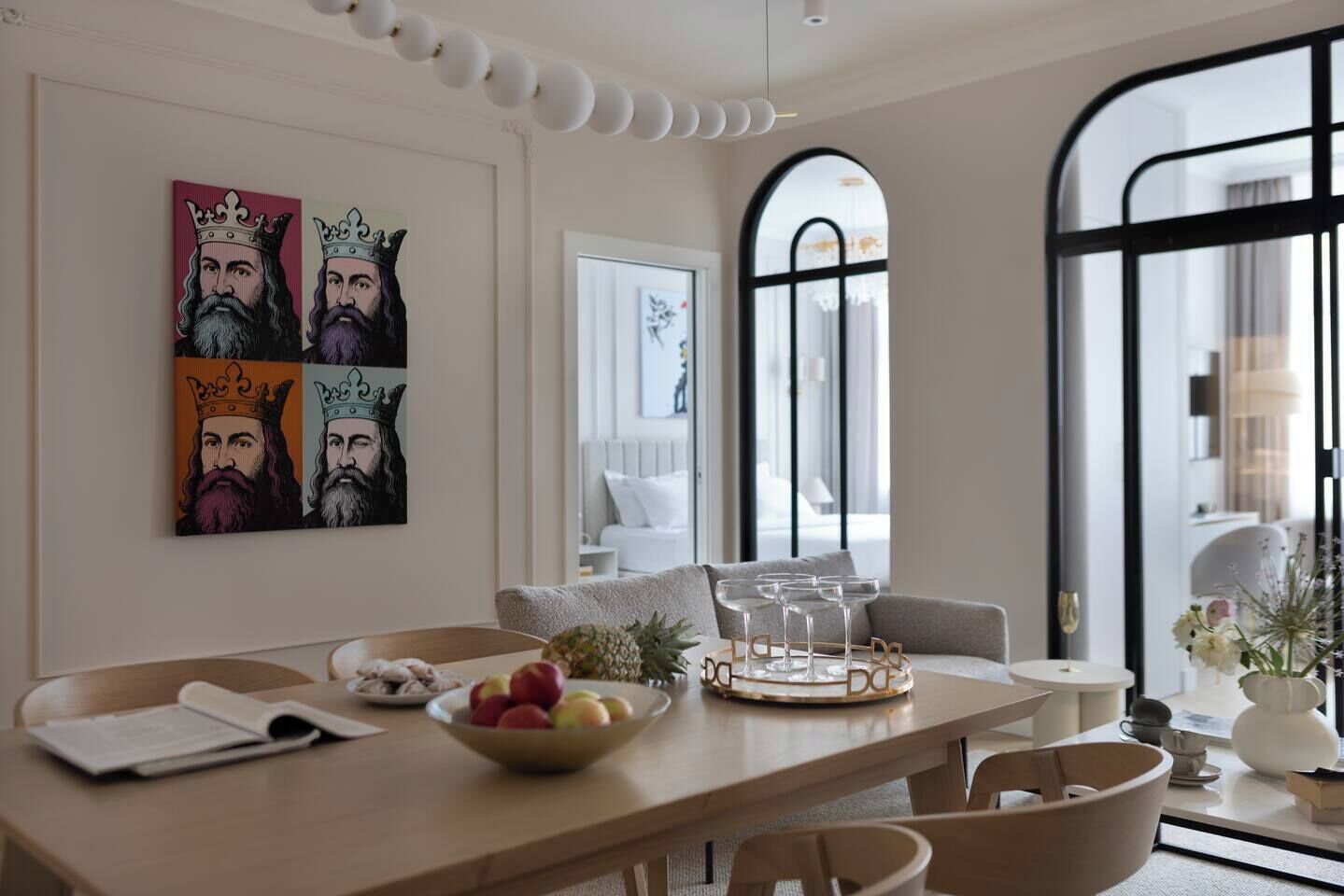 Un coin repas moderne avec une table en bois, des chaises, un saladier de fruits et un plateau décoratif.