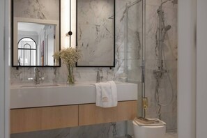 A modern bathroom with a marble vanity, a large mirror, a shower enclosure, and a vase with flowers. - Sandstone 2-Bed Apartment in the Heart of Kraków (Kraków)