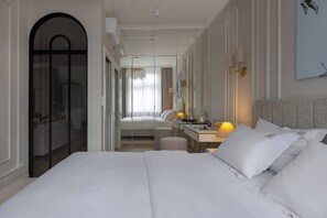 A hotel room with a large bed, a desk, a chair, a mirror, and a door. - Sandstone 2-Bed Apartment in the Heart of Kraków (Kraków)