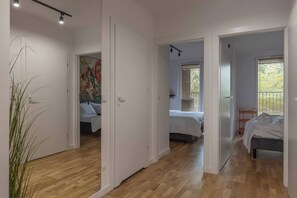 A modern interior with wooden floors, white walls, and multiple bedrooms with beds. - Cozy & Family-Friendly 2-bed Apartment (Kraków)