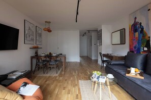 A modern living room with a sofa, coffee table, and dining area with chairs and a table. - Cozy & Family-Friendly 2-bed Apartment (Kraków)