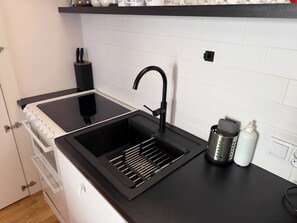 A kitchen with a black sink, a stainless steel kettle, and a white bottle. - Cozy & Family-Friendly 2-bed Apartment (Kraków)