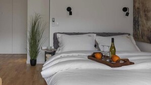 Una camera da letto moderna con un letto grande, un comodino, una pianta in vaso e un punto luce a parete.