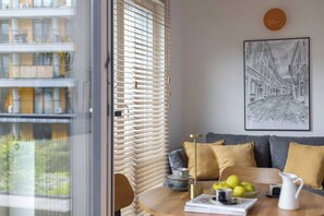 A room with a view of a building, a table with fruits and a pitcher, a sofa with cushions, and a framed artwork on the wall. - Comfy Studio for Two near Kazimierz (Kraków)