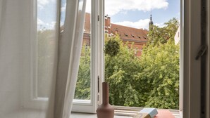 A window with a view of a brick building and trees. - Canvas House Porcelain 2-bed family apartment (Kraków)