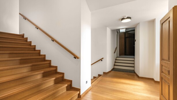 A wooden staircase with a handrail leading to a landing, followed by a second flight of stairs. - Canvas House Porcelain 2-bed family apartment (Kraków)