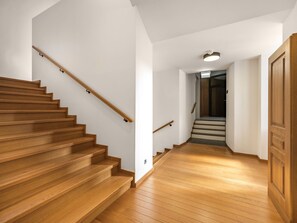 Un escalier en bois, doté d’une rampe, mène à un palier, puis s’ensuit un deuxième escalier.