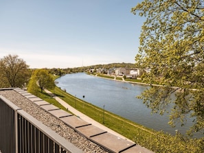 A riverside view with a walkway, buildings, and trees. - Vistula View Roof terrace 1-bed Apartment (Kraków)