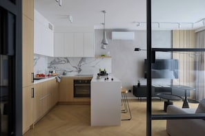 A modern kitchen with marble countertops, wooden cabinets, and a central island. - Vistula View Roof terrace 1-bed Apartment (Kraków)