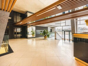 Eine großzügige Lobby mit modernem Design, darunter eine Holzdielendecke, große Fenster und Kübelpflanzen.