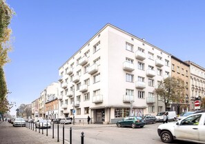 Ein mehrstöckiges Gebäude mit Balkonen, einem Geschäft und parkenden Autos in der Straße.