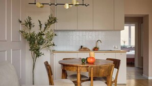 Een moderne keuken met witte kasten, een houten eettafel met stoelen en een hanglamp.