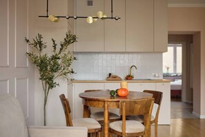 Eine moderne Küche mit weißen Schränken, einem Holzespeisetisch mit Stühlen und einer Pendelleuchte.