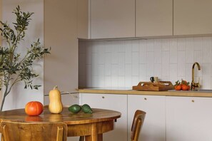 Eine Küche mit einem Holztisch, einer Pflanze und einer Obstschale.