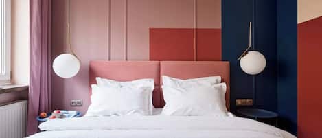 A bed with white bedding, a pink headboard, and two bedside lamps.
