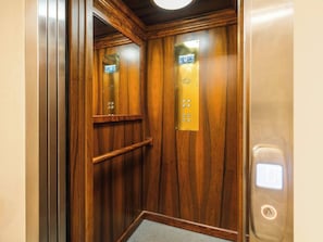 An elevator interior with wooden paneling, a handrail, and a control panel with buttons. - Art Palace 58m apartment with mezzanine (Kraków)