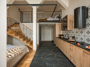 A modern kitchen with a black marble floor, wooden cabinets, and a black stove. - Art Palace 58m apartment with mezzanine (Kraków)