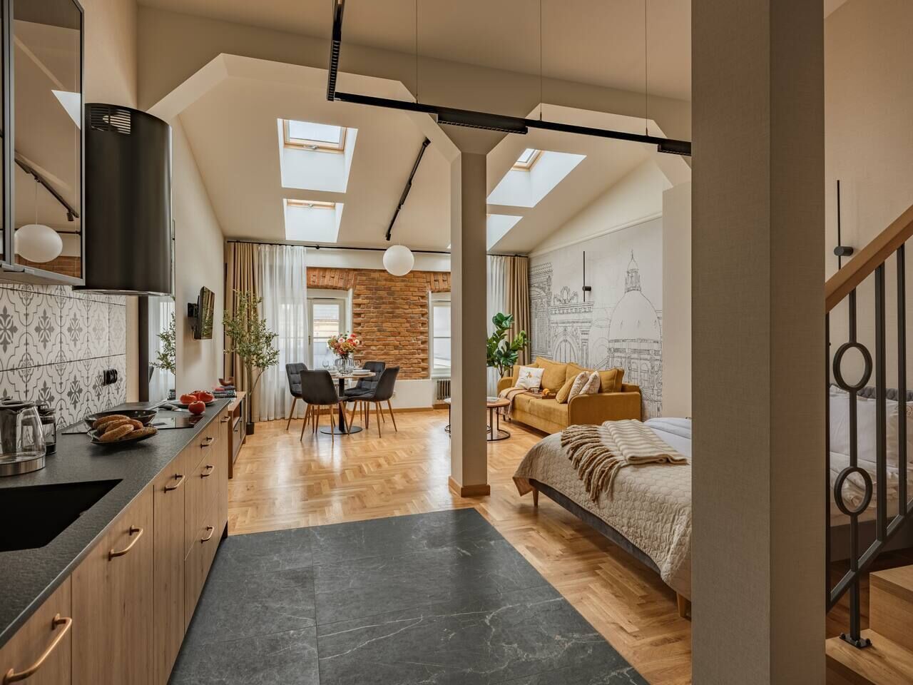 A modern interior with a kitchen, dining area, and bedroom, featuring skylights, wooden flooring, and a loft-style bed.