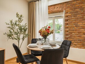 Ein Essbereich mit Backsteinwand, einem Fenster und einem für vier Personen gedeckten Tisch mit Stühlen.