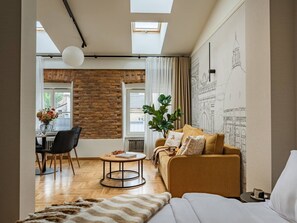 Ein modernes Wohnzimmer mit Sofa, Essbereich mit Tisch und Stühlen, großem Fenster und Dachfenster.