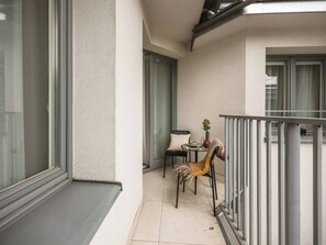 Ein Balkon mit Tisch, Stühlen, einer Topfpflanze und einem Geländer.
