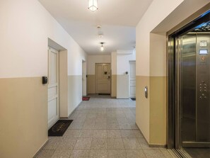 Ein Hotelflur mit einer Tür, einem Aufzug und einem gefliesten Boden.