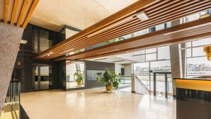 Eine großzügige Lobby mit modernem Design, darunter eine Holzdielendecke, große Fenster und Kübelpflanzen.