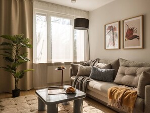 Ein Wohnzimmer mit einer Couch, einem Couchtisch, einer Stehlampe und einem Blumentopf.
