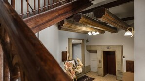 Eine Holztreppe mit dekorativer Decke und einer Tür mit der Aufschrift '2', die zu einem Raum mit einem Spiegel, einem gerahmten Bild und einer Fußmatte führt.