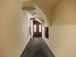 A hallway with a brick floor, arched ceiling, and a wooden door at the end. - Bauhaus Apartment 1-bed (Kraków)