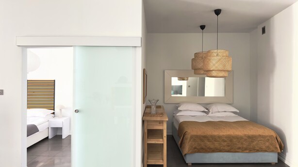 Ein Schlafzimmer mit einem Bett, einem Nachttisch, einem Spiegel und einer Hängeleuchte.