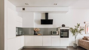 Eine moderne Küche mit weißen Schränken, einer schwarzen Dunstabzugshaube, einer Mikrowelle und einem Backofen.