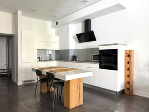 Eine moderne Küche mit weißen Schränken, einer Holzinsel und einem eingebauten Backofen.