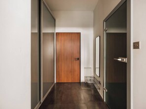 Ein Flur mit Holztür, Heizkörper und Metallregal.