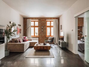 A modern living room with a brick wall, a sofa, a coffee table, and a TV. - Bauhaus Apartment 1-bed (Kraków)