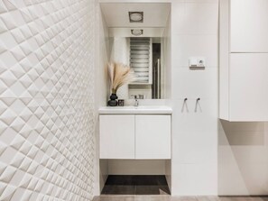 A modern bathroom with a white vanity, a mirror, and a towel rack. - Bauhaus Apartment 1-bed (Kraków)