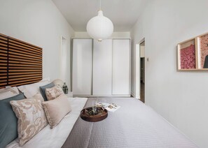 Quarto com cama, mesa de cabeceira e luminária pendente.