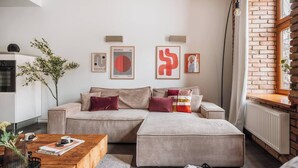 Ein modernes Wohnzimmer mit Sofa, Hocker, Couchtisch und Wandbildern.