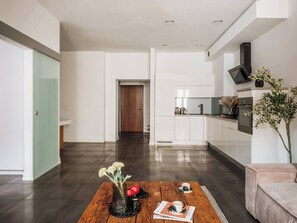 A modern kitchen with white cabinets, a built-in oven, and a black range hood. - Bauhaus Apartment 1-bed (Kraków)