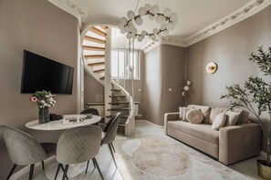 A modern living room with a staircase, a round table, and a sofa. - White Lotus - penthouse with roof terrace (Kraków)