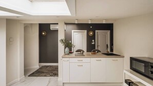 A modern kitchen with white cabinetry, a central island, and a built-in oven. - White Lotus - penthouse with roof terrace (Kraków)