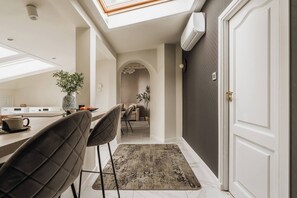 Una cocina moderna con tragaluces, un comedor con alfombra y un pasillo que conduce a una habitación oscura.