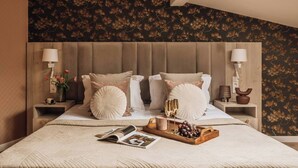 A bedroom with a large bed, two bedside tables, a nightstand, a window, and a wall with a floral pattern. - White Lotus - penthouse with roof terrace (Kraków)