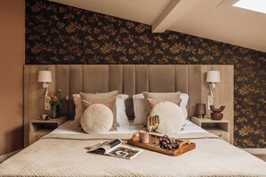 Ein Schlafzimmer mit einem großen Bett, zwei Nachttischen, einem Fenster und einer Wand mit floralem Muster.